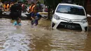 Dua orang anak bermain dekat mobil yang terendam banjir di permukiman Bukit Duri, Jakarta, Kamis (16/2). Meluapnya Bendungan Katulampa, Bogor, menyebabkan kawasan Bukit Duri tergenang air dengan ketinggian 10 - 80 cm. (Liputan6.com/Helmi Afandi)