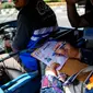 Seorang warga mengisi data saat menaiki bajaj bahan bakar gas (BBG) gratis dikawasan Monas Jakarta, Rabu (17/8). Selama satu minggu, PGN menyediakan total 700 bajaj gas atau 100 bajaj gas/hari. (Liputan6.com/Faizal Fanani)