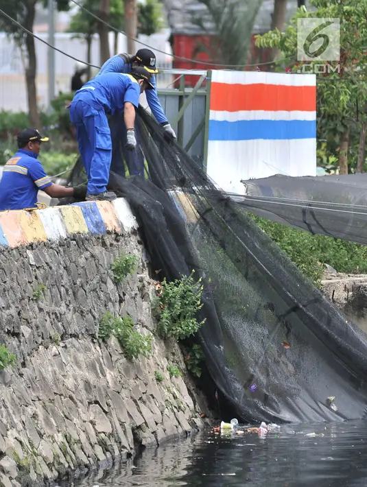 Petugas Dinas Sumber Daya Air Aliran Timur melepas kain waring atau jaring yang menutupi Kali Item di Kemayoran, Jakarta, Rabu (14/11). Pelepasan waring juga untuk mempermudah dalam membersihkan sampah di aliran Kali Item. (Merdeka.com/Iqbal S. Nugroho)