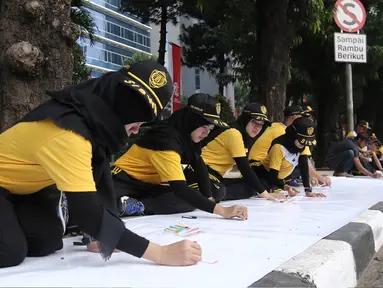 Peserta melukis di atas kanvas selebar 300 meter dalam acara lomba melukis massal di depan Kemenkumham, Jakarta, Minggu (13/8). Kegiatan ini dihadiri 140 murid sekolah dasar dan 320 peserta umum yang berdomisili di Jakarta. (Liputan6.com/Herman Zakharia)