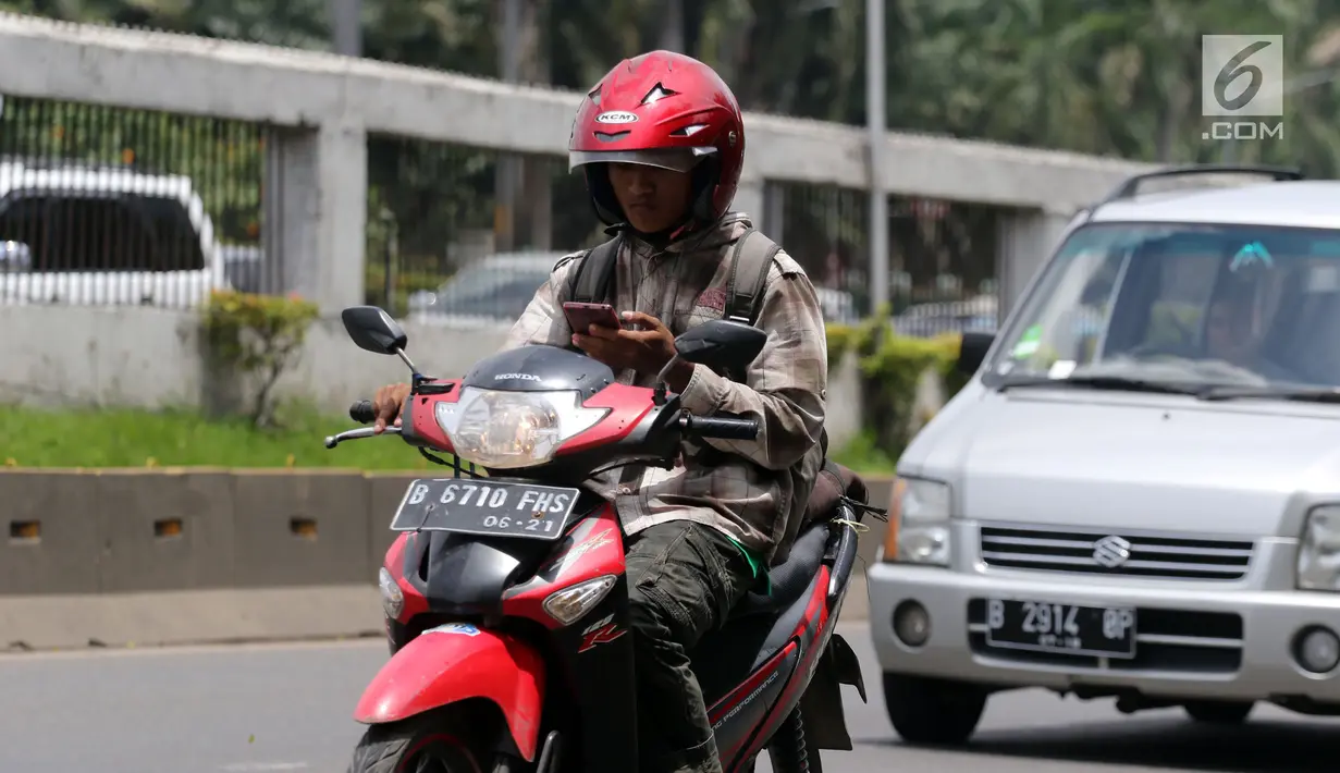 Pengendara menggunakan telepon seluler saat melaju dengan sepeda motornya di Jalan Gatot Subroto, Jakarta, Kamis (8/3). Dirlantas Polda Metro Jaya akan menindak orang yang menggunakan telepon seluler saat aktivitas lalu lintas.(Liputan6.com/Arya Manggala)