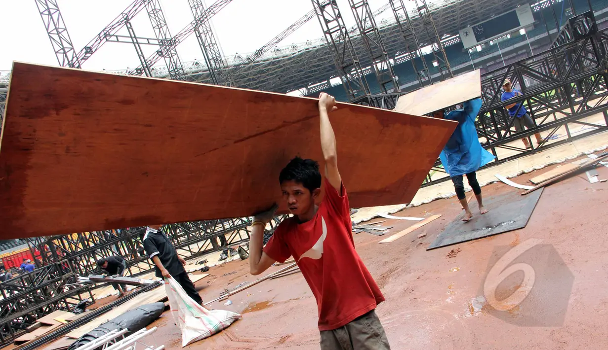 Pekerja membongkar penutup rumput (grass cover) usai konser One Direction di Stadion Utama Gelora Bung Karno (SUGBK), Jakarta, Kamis (26/3/2015). Lapangan SUGBK akan dipersiapkan untuk Pra-Piala Asia U-23. (Liputan6.com/Helmi Afandi)