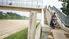 Pengendara sepeda motor melintasi JPO yang melintang di atas Tol Cijago Seksi II di Depok, Jawa Barat, Rabu (15/5). Meskipun berbahaya, namun curamnya akses JPO tidak menjadi penghalang bagi sebagian pemotor untuk menyeberang agar dapat memersingkat waktu tempuh. (Liputan6.com/immanuel Antonius)