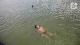 Seorang anak berenang di Danau Sunter, Jakarta, Selasa (2/2/2021). Minimnya lahan bermain anak membuat mereka memanfaatkan tempat yang tidak semestinya untuk bermain karena adanya risiko hanyut dan tenggelam bila tidak mampu untuk berenang. (Liputan6.com/Faizal Fanani)