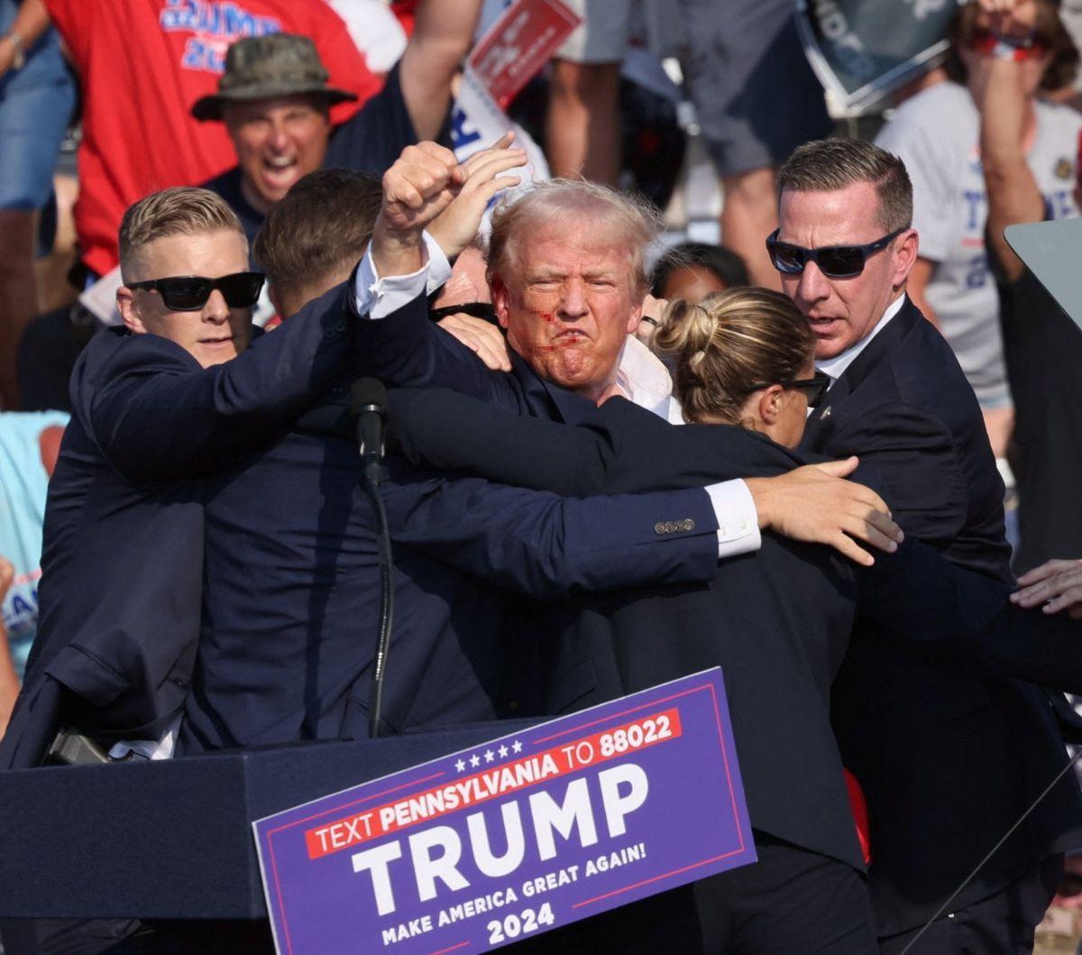 Mantan presiden Amerika Serikat yang juga kandidat presiden dari Partai Republik, Donald Trump mengangkat kepalan tangannya seraya mendapatkan perlindungan dari body guard setelah ditembak saat kampanye di&nbsp;Butler Farm Show, Butler, Pennsylvania, Amer