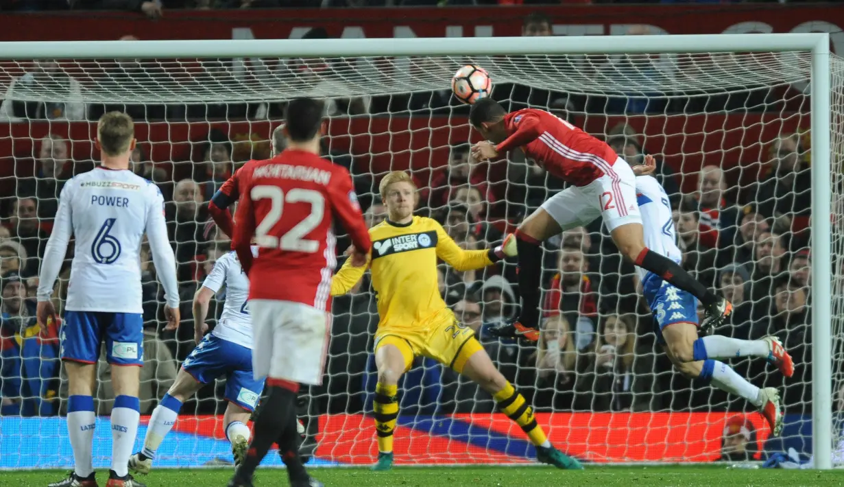 Bek MU, Chris Smalling berusaha menyundul bola ke arah gawang Wigan Athletic saat bertanding di Stadion Old Trafford, Inggris (29/1). Manchester United  melaju ke babak 16 besar Piala FA. (AP Photo/Rui Vieira)
