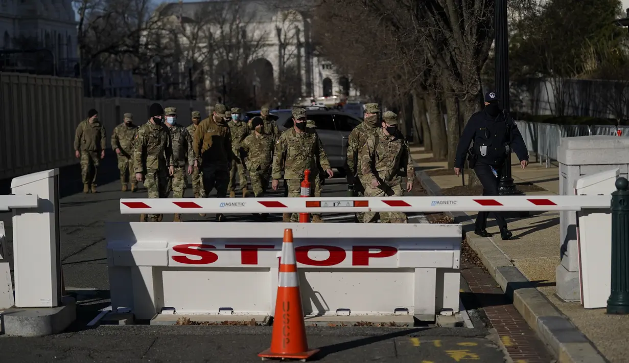Pasukan Garda Nasional berjalan di halaman Capitol Hill sehari setelah massa pendukung Donald Trump menerobos masuk ke Gedung Capitol, Washington, DC. Kamis (7/1/2021). Penyerbuan dilakukan saat para anggota Kongres hendak mengesahkan kemenangan Joe Biden. (AP Photo/Evan Vucci)