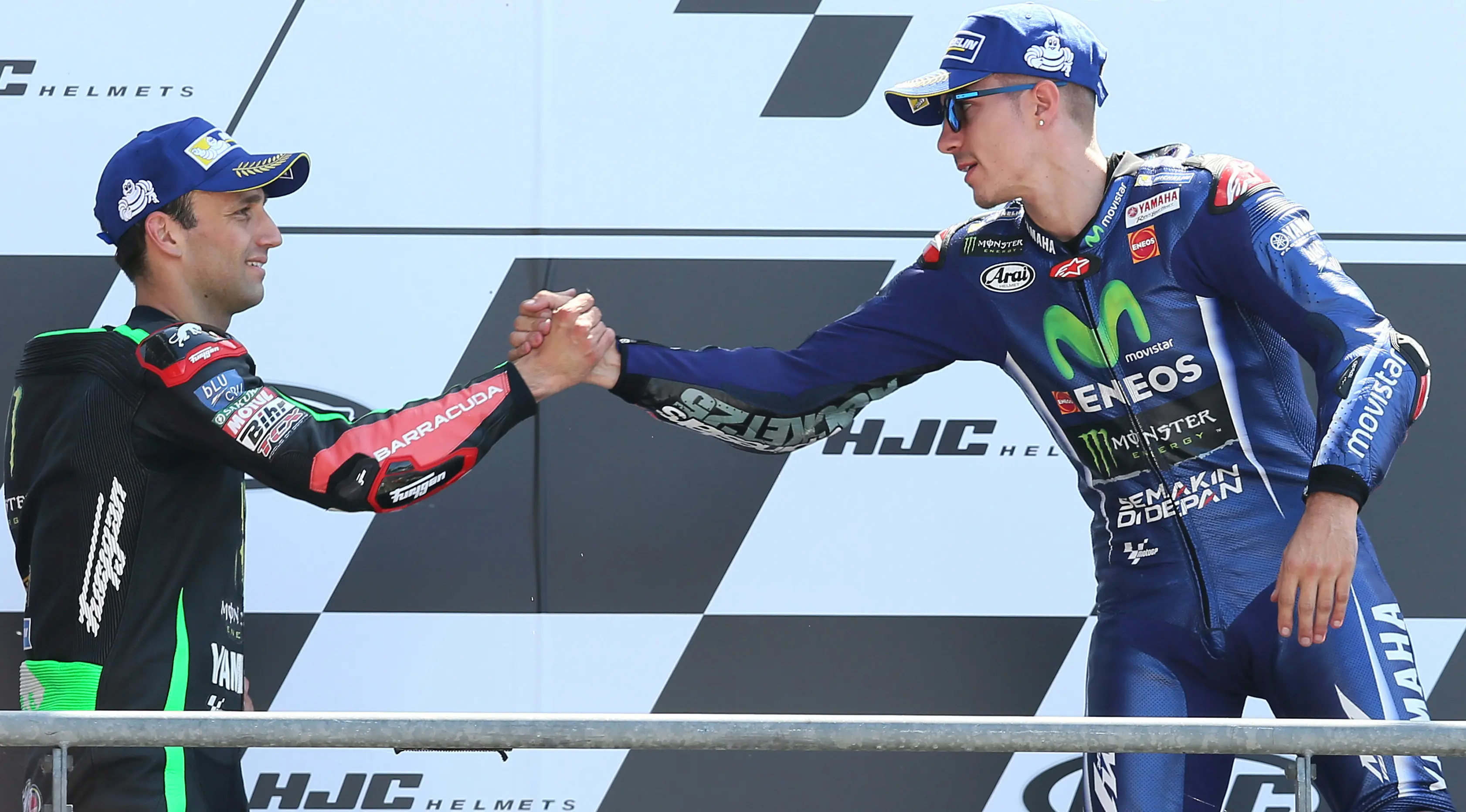 Pembalap Movistar Yamaha dan Tim Yamaha Tech 3, Maverick Vinales dan Johann Zarco saling berjabat tangan di atas podium MotoGP Prancis, Minggu (21/5). Vinales menjuarai MotoGP Prancis disusul Zarco yang menempati posisi kedua. (AP Photo/David Vincent)