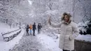 Orang-orang berpose di bawah pohon yang tertutup salju di Central Park setelah badai salju pertama musim dingin 2022 di New York City, Jumat (7/1/2022). Badai musim dingin membawa lebih dari 15 cm salju di bagian timur Amerika Serikat (AS), menutup sekolah, kantor dan jalan-jalan. (Ed JONES / AFP)