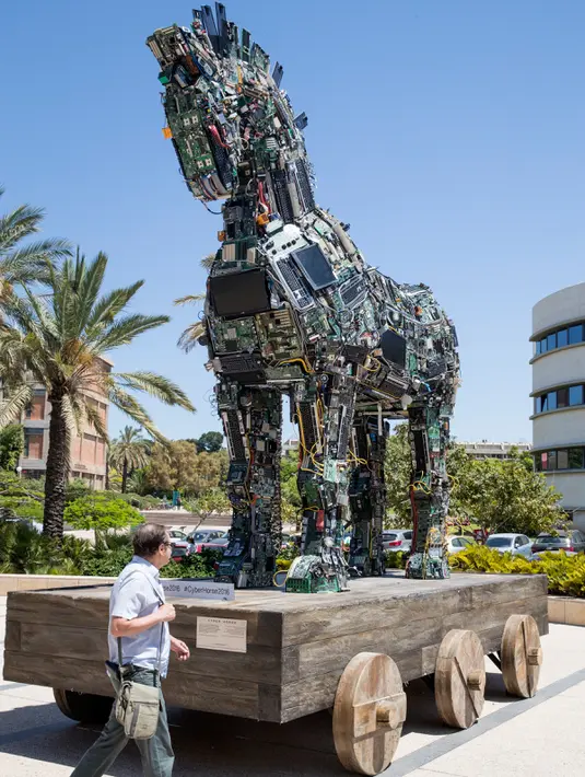 Seorang pengunjung melewati replika patung kuda troya "Cyber Horse" yang terbuat dari ribuan komputer dan komponen ponsel yang terinfeksi virus, di pintu masuk konferensi Cyber Week tahunan di Tel Aviv University, Israel, Senin (20/6). (Jack GUEZ/AFP)