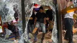 Pria memecahkan kaca saat unjuk rasa di Asuncion, Paraguay (31/3). Aksi dilakukan setelah Senat kedapatan menggelar voting rahasia untuk amandemen konstitusi, yang mengizinkan Presiden Horacio Cartes mencalonkan diri kembali. (AP Photo/Jorge Saenz)