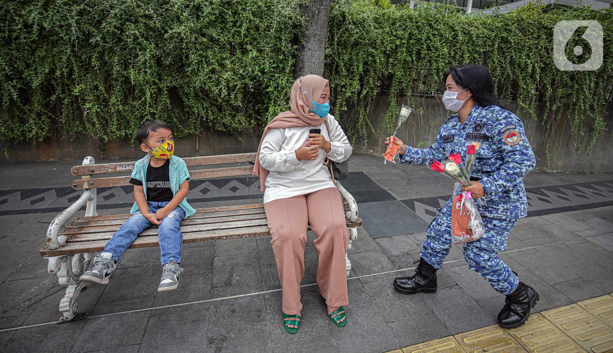 Perserta yang tergabung dalam Forum Kader Bela Negara DKI Jakarta membagikan bunga dan masker kepada warga di Jalan Thamrin, Jakarta, Rabu (22/12/2021). Aksi tersebut merupakan bentuk apresiasi terhadap kaum perempuan terutama pada peringatan Hari Ibu. (Liputan6.com/Faizal Fanani)