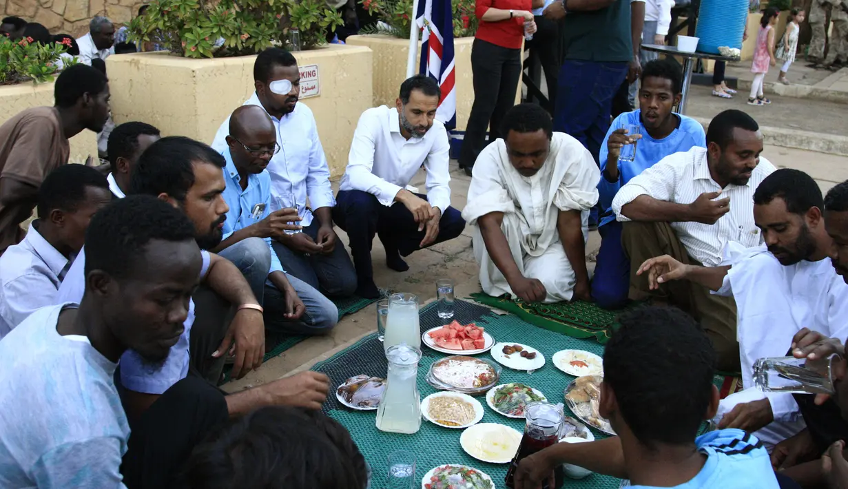 Sejumlah pria Sudan menikmati makanan buka puasa selama bulan suci Ramadan di depan kedubes Inggris di ibukota Khartoum (23/5/2019). Duta Besar Inggris untuk Sudan, Irfan Sidiq menggelar buka puasa bersama di ibu kota tersebut. (AFP Photo/Ebrahim Hamid)