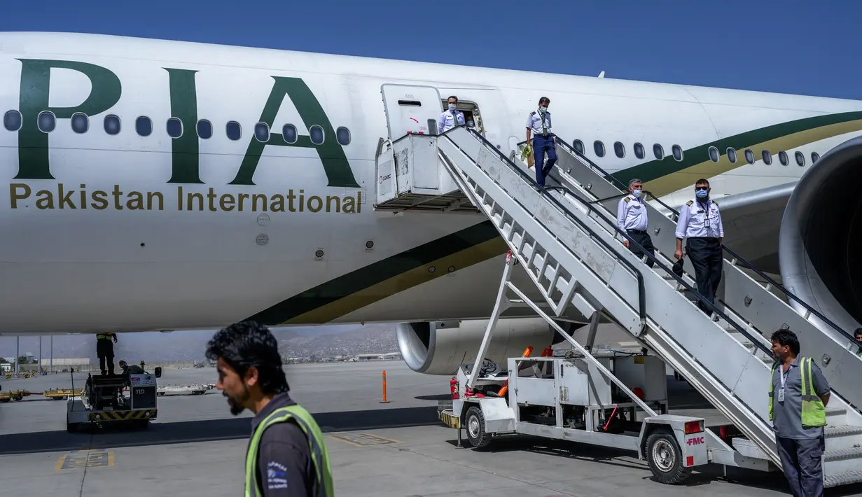 Kru pesawat turun dari penerbangan Pakistan International Airways (PIA), di bandara di Kabul, Senin (13/9/2021). Pesawat itu tercatat sebagai penerbangan komersial internasional pertama yang mendarat sejak Taliban merebut kembali kekuasaan di Afghanistan pada Agustus lalu. (Bulent KILIC/AFP)