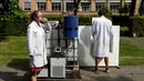 Ilmuwan Belgia, Marjolein Vanoppen dan Sebastiaan Derese menjajal mesin yang bisa mengubah air seni menjadi air yang layak diminum dan menjadi pupuk dengan bantuan energi matahari di University of Ghent, Belgia, Selasa (26/7). (REUTERS/Francois Lenoir)