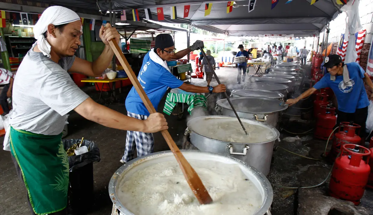 Sejumlah orang mengaduk Bubur Lambuk di desa Kampung Baru, Kuala Lumpur, Malaysia, Kamis (1/6). Bubur Lambuk adalah bubur yang terbuat dari beras dengan campuran rempah dan sayuran. (AP/Daniel Chan)
