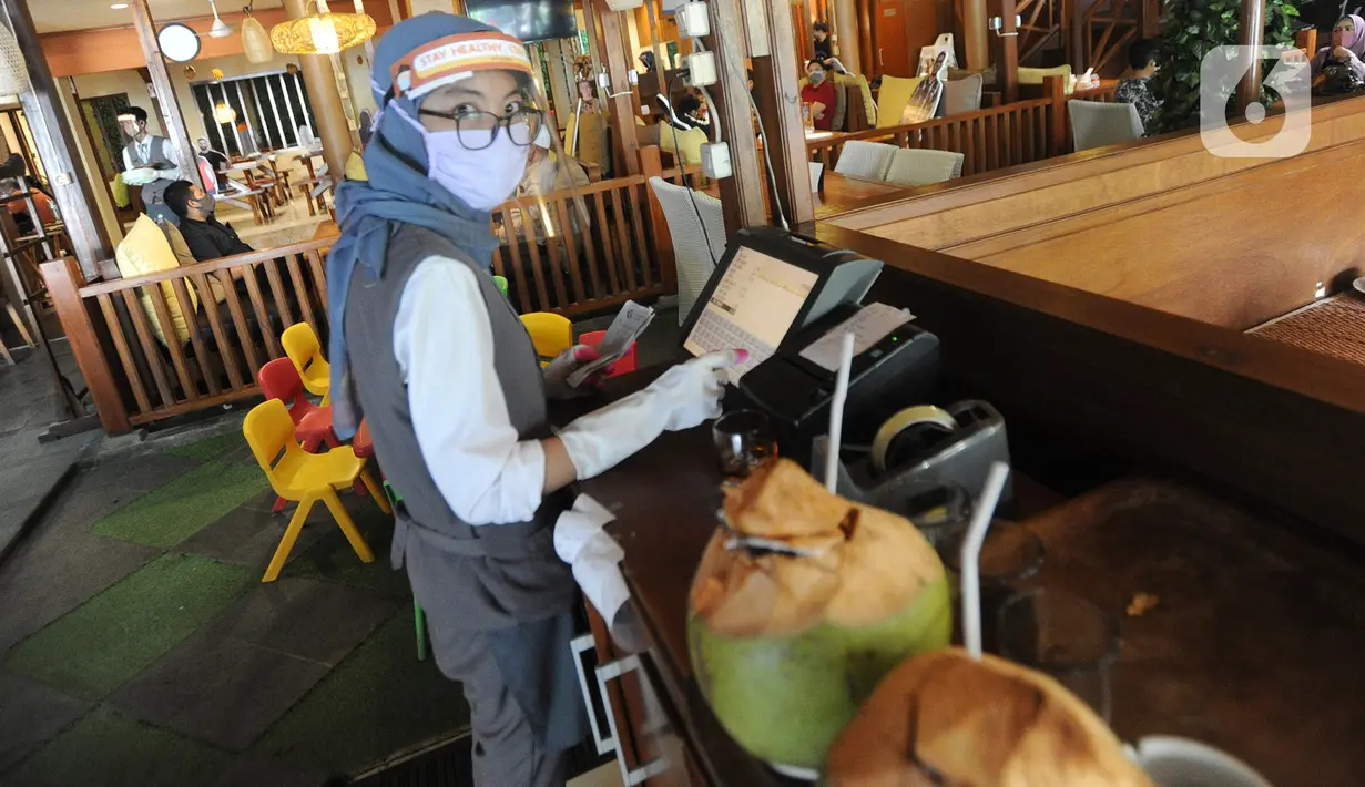 Kasir menggunakan pelindung wajah, masker dan sarung tangan di Rumah Makan Bumi Aki, Pajajaran, Kota Bogor, Minggu  (31/5/2020). Sejumlah restoran dan rumah makan di Bogor mulai membuka layanan makan di tempat dengan protokol kesehatan ketat guna mengatasi pandemi COVID-19. (merdeka.com/Arie Basuki)