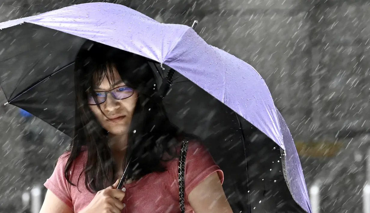 Ekpsresi wanita Taiwan saat berjalan melawan hembusan angin kencang yang ditimbulkan oleh topan Lekima di Taipei, Taiwan, Jumat (9/8/2019). Topan  tersebut dinilai sebagai yang terkuat menghantam Taiwan di tahun ini. (AFP Photo/Sam Yeh)