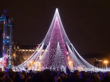 Sejumlah pasangan berdiri di depan pohon Natal raksasa yang menerangi Alun-Alun Katedral di Vilnius, Lithuania, 1 Desember 2017. Pohon Natal megah itu memiliki tinggi sekitar 30 meter yang berhias 70 ribu lampu dan 900 mainan. (AP Photo/Mindaugas Kulbis)