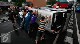 Sejumlah warga berusaha membalikkan mini bus dengan Nopol E 7054 K yang terguling di Jalan Lingkar Yogyakarta, Senin (9/5). Akibat kecelakaan tersebut jalur lingkar menuju Solo dan Kota Yogyakarta mengalami kemacetan. (Liputan6.com/Boy Harjanto)