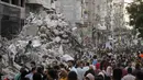 Orang-orang melewati tumpukan puing di samping bangunan yang hancur oleh serangan udara Israel, di Kota Gaza, Jumat (21/5/2021). Israel dan Hamas telah sepakat untuk gencatan senjata di Jalur Gaza setelah 11 hari pertempuran. (AP Photo/John Minchillo)