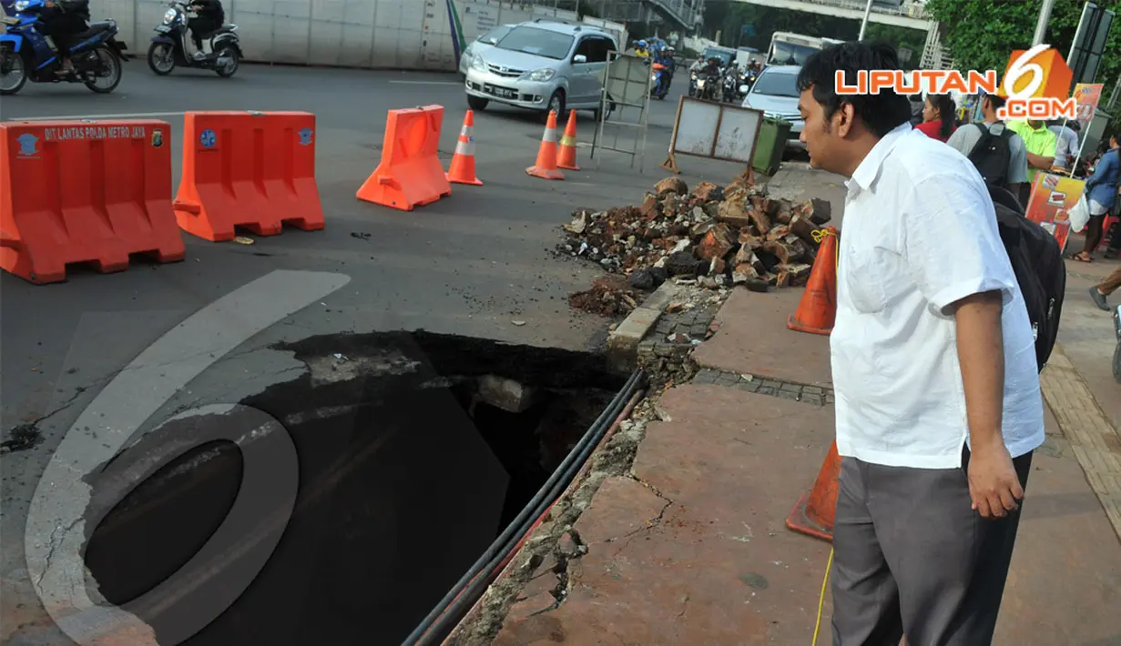 Seorang pejalan kaki tampak melihat jalan yang amblas di kawasan Sudirman. . Kamis (10/4/2014)  (Liputan6.com/Johan Tallo).