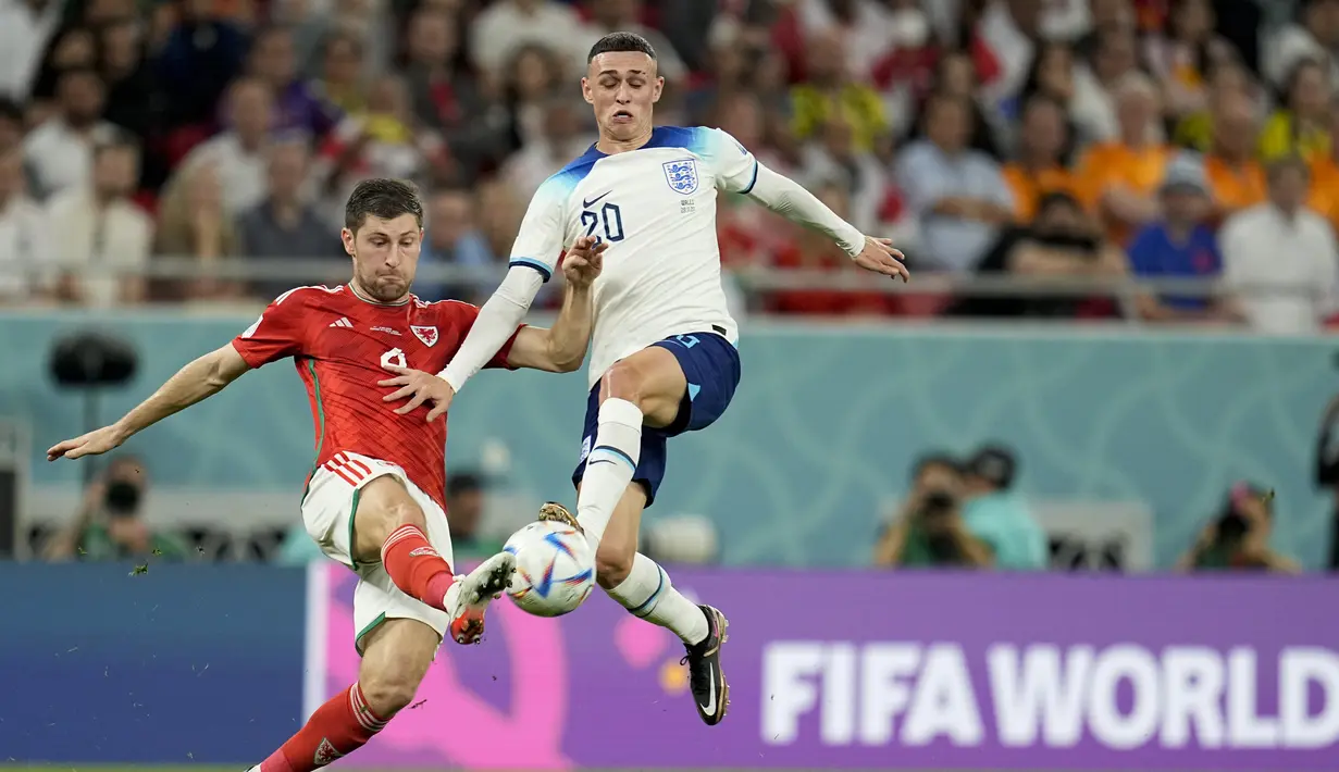 <p>Pemain Inggris, Phil Foden (kanan) berebut bola dengan pemain Wales,&nbsp;Ben Davies saat matchday ketiga Grup B Piala Dunia 2022 di Ahmad Bin Ali Stadium, Rabu (30/11/2022). (AP/Abbie Parr)</p>