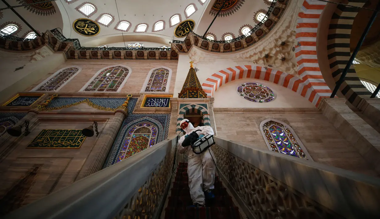 Pekerja mengenakan pakaian pelindung menyemprotkan disinfektan bagian dalam Masjid Suleymaniye yang bersejarah pada hari ketiga Idul Fitri di Istanbul, Selasa (26/5/2020). Beberapa masjid didisinfektan sebelum dibuka kembali pada 29 Mei usai ditutup selama lebih dari enam minggu. (AP/Emrah Gurel)