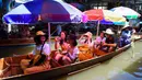 Wisatawan naik perahu di pasar terapung Damnoen Saduak, Bangkok, Thailand, Jumat (21/6/2019). Paling enak, datang ke sini untuk berwisata kuliner karena itulah yang menjadi salah satu daya tarik Thailand yakni street food. (TANG CHHIN Sothy/AFP)