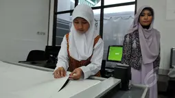 Salah satu pengajar mengawasi siswi yang sedang menggunting pola gaun muslim di sela-sela peresmian Sekolah Fashion SMK NU Banat, Kudus, Jawa Tengah, Rabu (11/3/2015). (Liputan6.com/Panji Diksana)