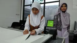 Salah satu pengajar mengawasi siswi yang sedang menggunting pola gaun muslim di sela-sela peresmian Sekolah Fashion SMK NU Banat, Kudus, Jawa Tengah, Rabu (11/3/2015). (Liputan6.com/Panji Diksana)
