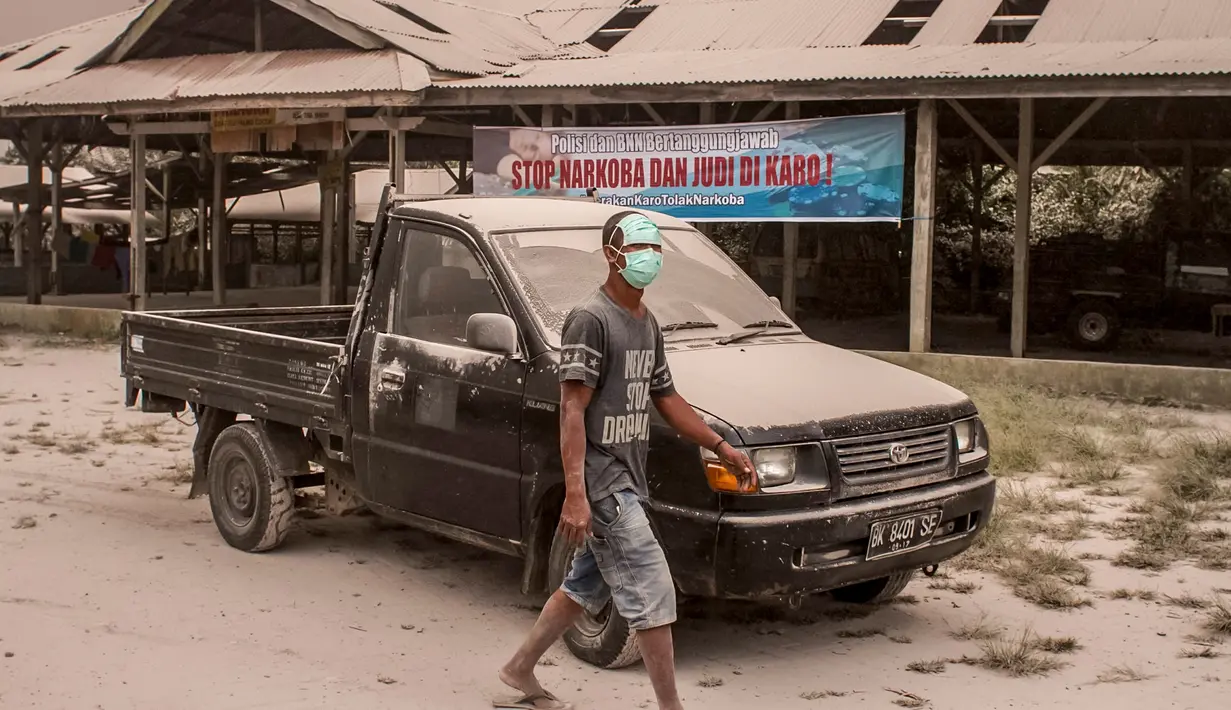 Warga menutupi wajahnya untuk menghindari abu vulkanik akibat erupsi Gunung Sinabung yang menghujani Desa Tiga Pancur, Karo, Sumatera Utara, Rabu (2/8). Tidak ada korban jiwa meski wilayah Kabupaten Karo diselimuti abu vulkanis. (IVAN DAMANIK/AFP)