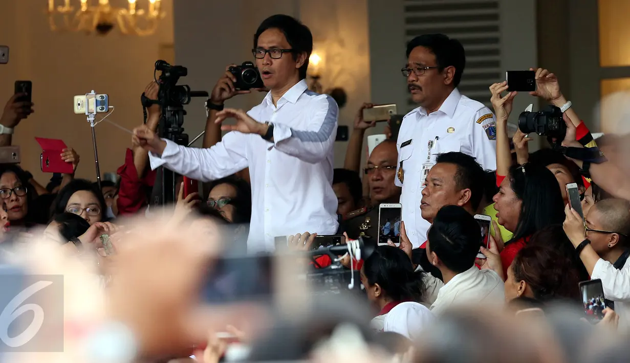 Musisi Addie MS didampingi Plt Gubernur DKI Jakarta, Djarot Saiful Hidayat memimpin warga menyanyikan lagu nasional di Balai Kota DKI Jakarta, Rabu (10/5). Ini merupakan aksi simpatik terhadap vonis yang dijatuhkan kepada Ahok. (Liputan6.com/Johan Tallo)