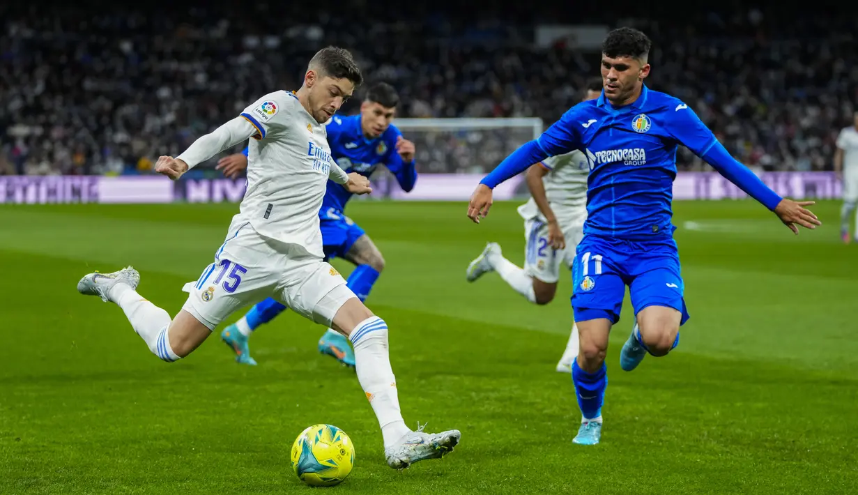 Gelandang Real Madrid, Federico Valverde berusaha mengumpan bola dari kawalan pemain Getafe, Carles Alena pada pertandingan lanjutan La Liga Spanyol di stadion Santiago Bernabeu di Madrid, Minggu (10/4/2022). Real Madrid menang atas Getafe 2-0. (AP Photo/Manu Fernandez)