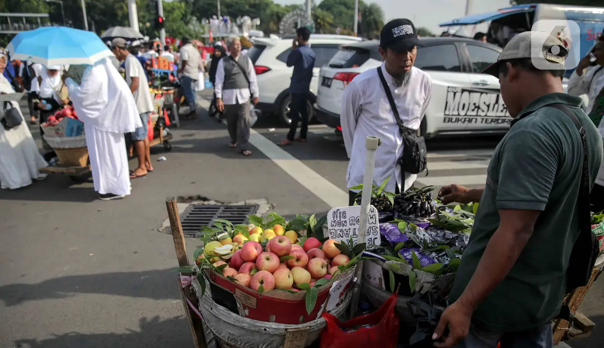 Pedagang buah melayani pembeli saat berjualan di tengah aksi reuni 212, sekitaran Jalan Medan Merdeka Barat, Jakarta, Senin (2/12/2019). Sejumlah PKL meraup untung dengan berjualan di tengah ribuan massa Persaudaraan Alumni 212 yang mengikuti reuni di Monas. (Liputan6.com/Faizal Fanani)