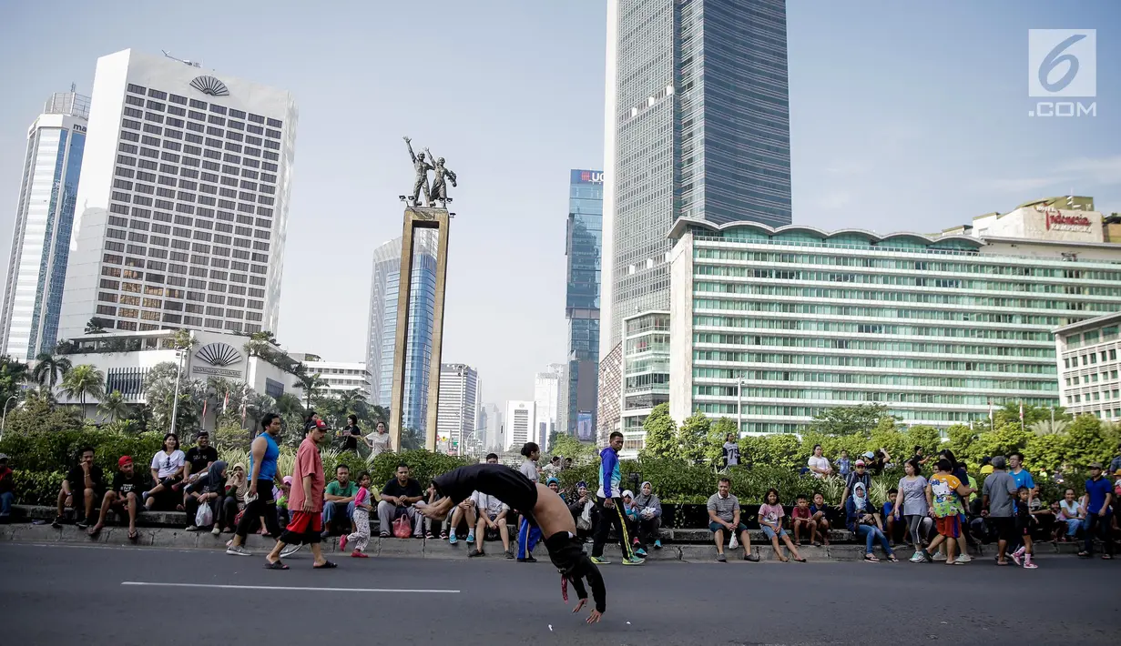 Seorang pria melakukan atraksi berjalan dengan tangan di area Car Free Day kawasan MH Thamrin, Jakarta, Minggu (4/6). Pria yang tergabung dalam kelompok seniman Kuda Lumping itu melakukan aksi berbahaya untuk mencari nafkah. (Liputan6.com/Faizal Fanani)