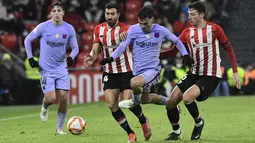 Penyerang Barcelona, Pedri (tengah) membawa bola dari kawalan pemain Athletic Bilbao, Mikel Vesga dan Inigo Martinez pada pertandingan babak 16 besar Copa del Rey Cup Spanyol di stadion San Mames di Bilbao, Jumat (21/1/2022). Athletic Bilbao menang tipis atas Barcelona 3-2. (AP Photo/Alvaro Barrient