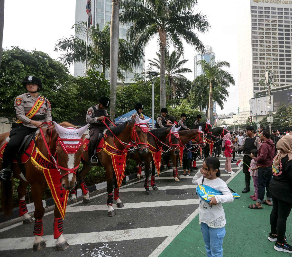 Seorang anak melihat Polisi Berkuda dari Detasemen Turangga Direktorat Polisi Satwa Polri yang dihadrikan pada Hari Bebas Kendaraan Bermotor di kawasan Bundaran HI, Jakarta, Minggu (13/8/2023).