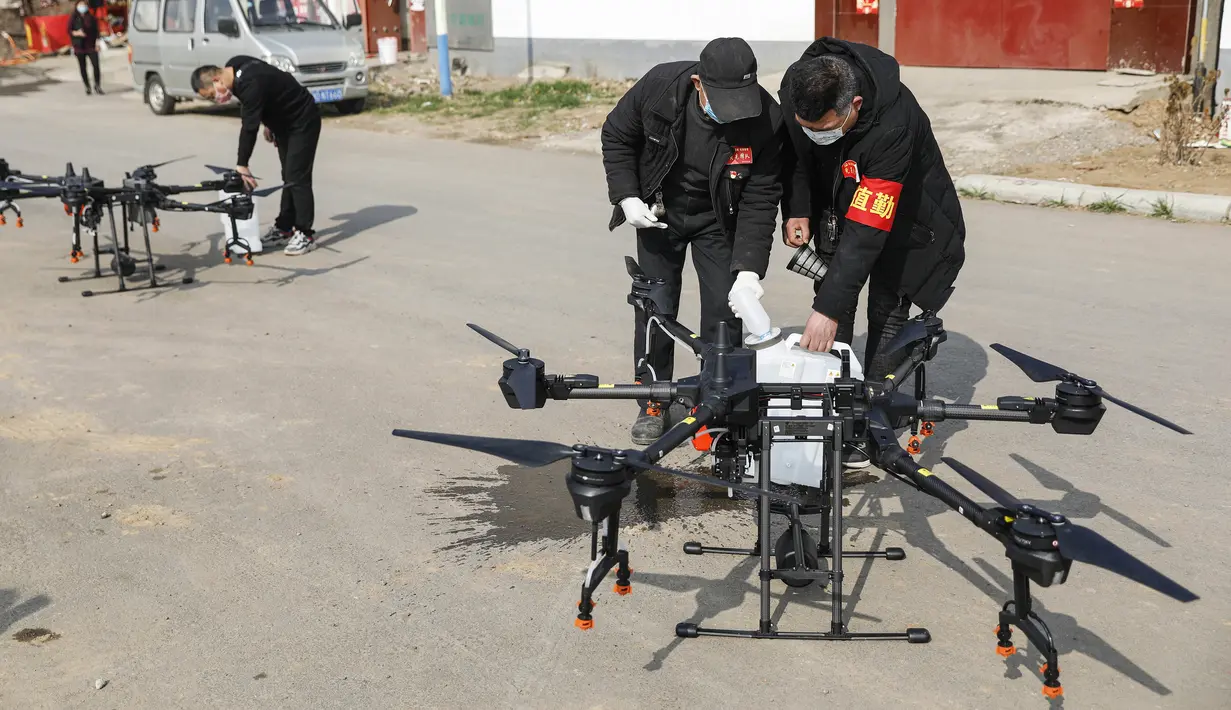 Warga memasukan cairan disinfektan yang akan dibawa drone sebelum melakukan penyemprotan di sebuah desa di Pingdingshan, di Provinsi Henan, China (31/1/2020). Warga Henan di China memanfaatkan teknologi drone untuk menyemprotkan cairan disinfektan dari udara.  (AFP Photo/Str)
