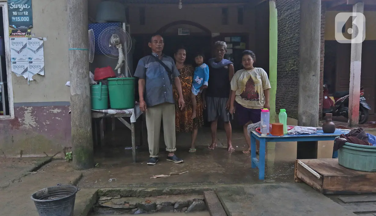 Keluarga Pak Warta berpose di depan kediamannya Desa Sumber Urip Pebayuran, Kabupaten Bekasi, Jawa Barat, Senin (22/2/2021). Banjir merenda keluarga tersebut merapikan barang-barang dan bersihkan rumah yang sudah surut. (Liputan6.com/Herman Zakharia)