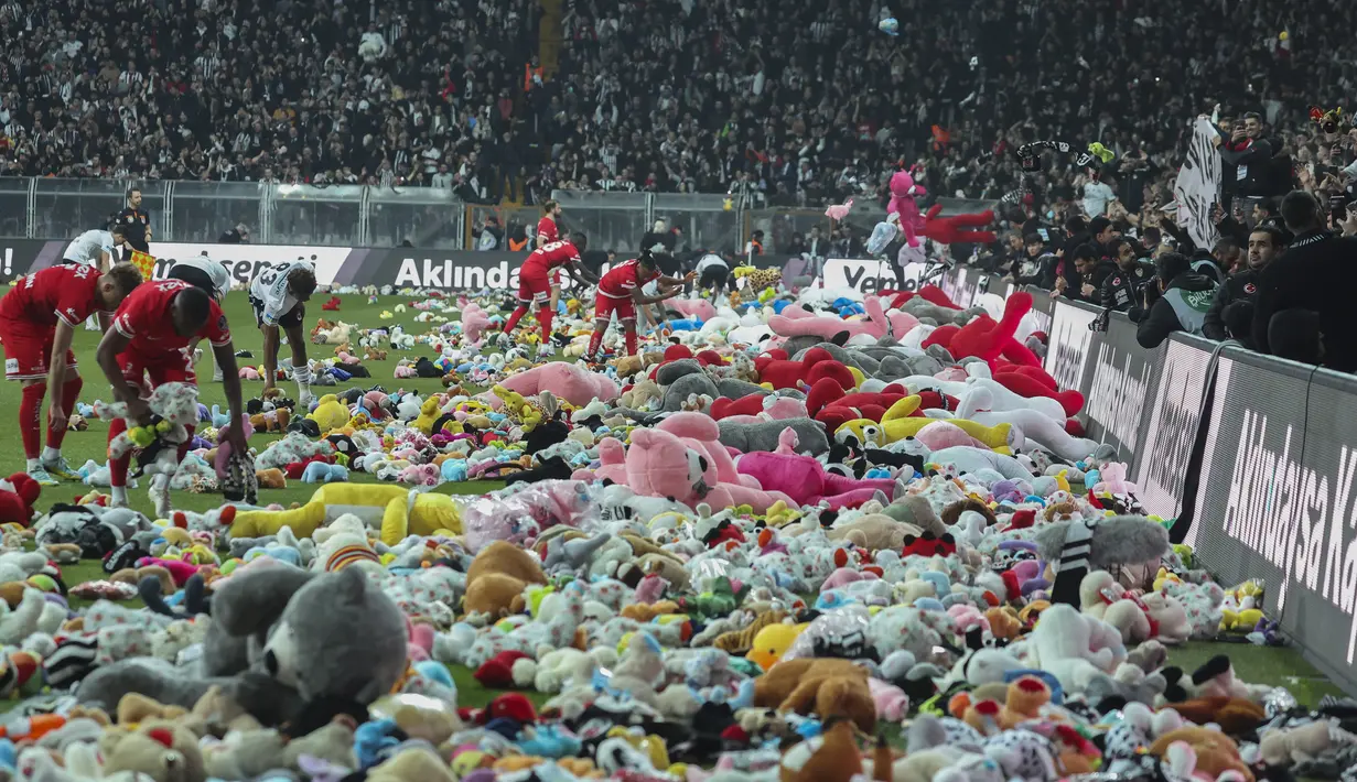 Suporter melempar mainan ke lapangan selama pertandingan Liga Turki (Super Lig) antara Besiktas dan Antalyaspor di stadion Vodafone di Istanbul, Minggu (26/2/2023). Ribuan mainan akan dikirim ke anak-anak di daerah yang terkena dampak gempa Tukri , banyak dari mereka mengungsi setelah rumah mereka dihancurkan. (AP Photo)