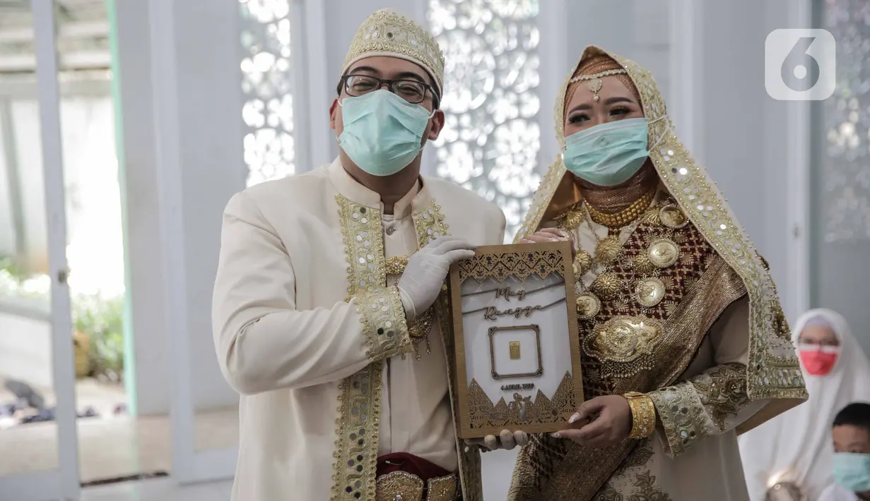 Sepasang pengantin seusai melaksanakan akad nikah di kawasan Pancoran, Jakarta, Rabu (1/4/2020). Pasangan tersebut menggelar pernikahan yang hanya dihadiri pihak keluarga mempelai guna menghindari pertemuan dengan orang banyak dan meminimalkan penyebaran COVID-19. (Liputan6.com/Faizal Fanani)