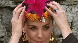 Duchess of Cambridge, Kate Middleton marapikan topi tradisional suku Kalash selama kunjungannya ke Lembah Bumburate di Distrik Chitral utara Pakistan (16/10/2019). Kate Middleton tampil cantik berpenampilan dengan topi tradisional Suku Kalash. (AFP Photo/Farooq Naeem)