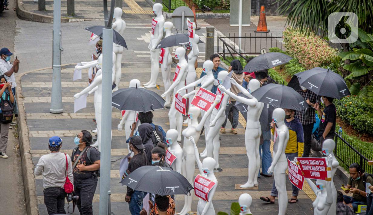 Aktivis membawa manekin dengan poster saat menggelar aksi di depan Polda Metro Jaya, Senin (21/3/2022). Aksi tersebut bentuk dukungan terhadap Haris Azhar dan Fatia Maulidiyanti saat menjalani pemeriksaan terkait kasus dugaan pencemaran nama baik Luhut Binsar Pandjaitan. (Liputan6.com/Faizal Fanani)