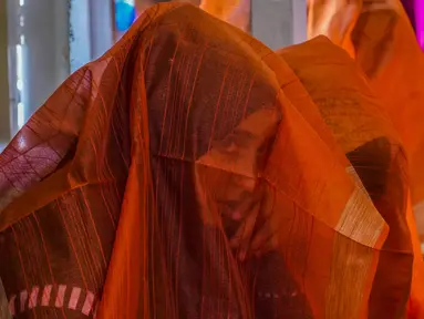 Seorang pengantin Muslim Kashmir melihat melalui kerudungnya saat acara pernikahan massal di Srinagar, Kashmir yang dikuasai India, Kamis, 15 Juni 2023.(AP Photo/Mukhtar Khan)