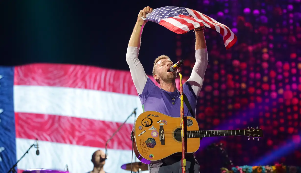 Vokalis grup band Coldplay, Chris Martin mengibarkan bendera Amerika Serikat saat menghibur para penonton di Lapangan FedEx di Landover, Md, AS (6/8). (Photo by Brent N. Clarke/Invision/AP)