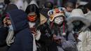 Warga yang mengenakan masker mengantre di luar toko yang menjual memorabilia resmi Olimpiade di Beijing, Senin, 21 Februari 2022. Boneka maskot Olimpiade Bing Dwen Dwen masih tetap populer meskipun Olimpiade Musim Dingin Beijing telah berakhir. (AP Photo/Andy Wong)