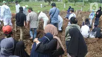 Keluarga menyaksikan pemakaman jenazah korban COVID-19 di TPU Tegal Alur, Jakarta, Kamis (17/12/2020). Hingga hari ini, intensitas pemakamanan korban covid-19 di DKI masih tinggi dengan rata-rata yang dimakamkan mencapai 30 hingga 38 jenazah per hari. (merdeka.com/Arie basuki)