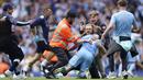 Para suporter tampak memeluk pemain Manchester City, Kevin De Bruyne, saat merayakan gelar juara Liga Inggris 2021 / 2022 di Stadion Etihad, Minggu (23/5/2022). (AP/Dave Thompson)