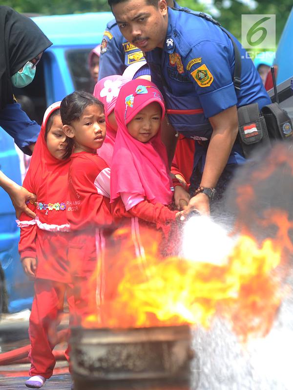 Petugas mendampingi siswa TK di lingkungan Kabupaten Bogor yang mencoba alat pemadam kebakaran di kantor Dinas Pemadam Kebakaran, Jalan Tegar beriman, Cibinong, Rabu (18/9/2019). Kegiatan belajar di luar kelas ini untuk mengenalkan profesi dan tugas pemadam kebakaran. (merdeka.com/Arie Basuki)